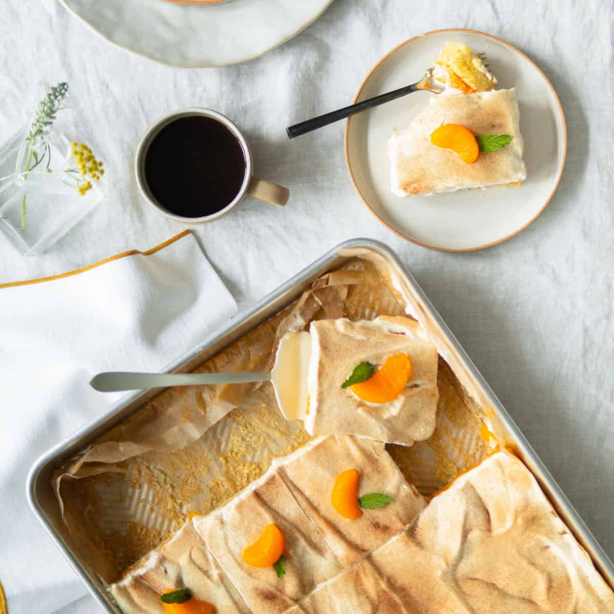 Orange cake in a cake pan decorated with mandarin oranges.