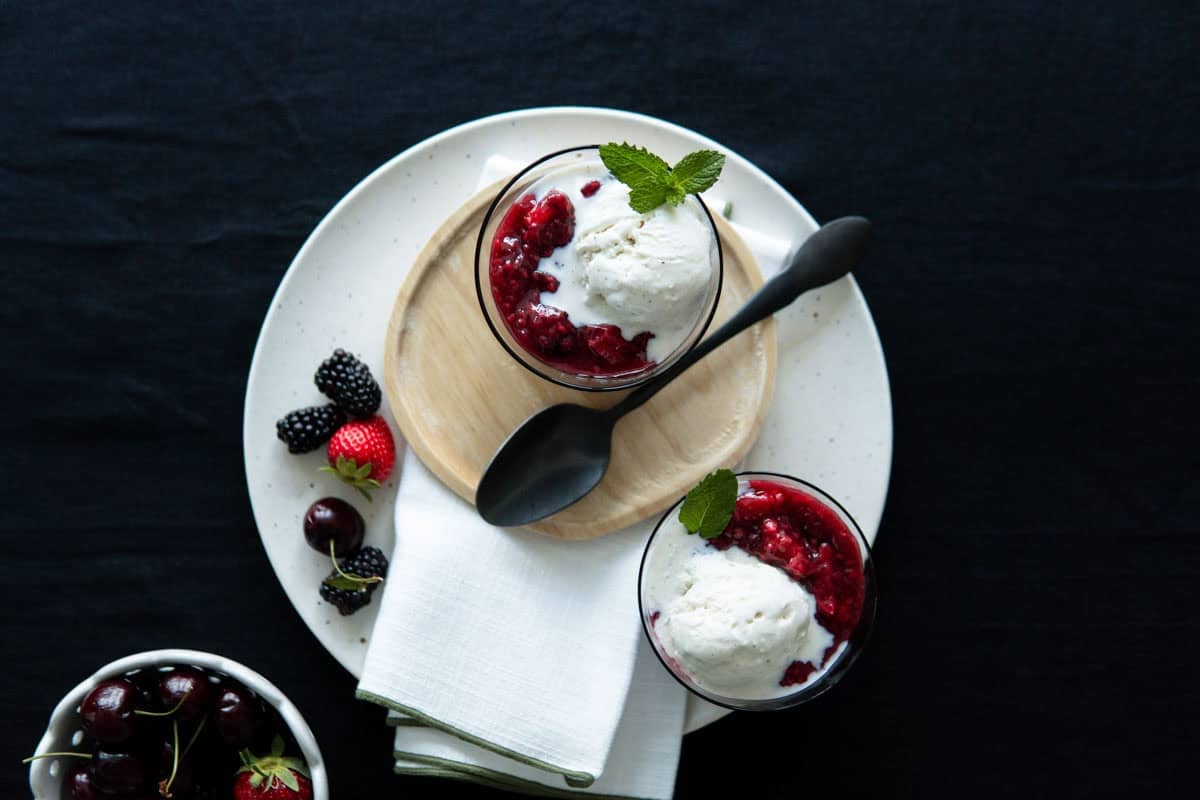 Rote Grütze with half-melted ice cream over the top of it and garnished with mint leaves.