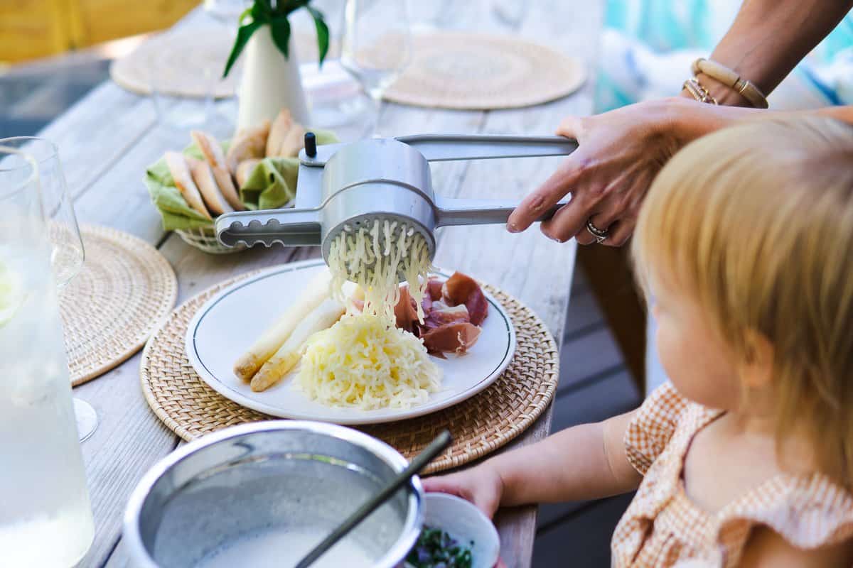 pressing potato snow onto a plate with white asparagus and ham