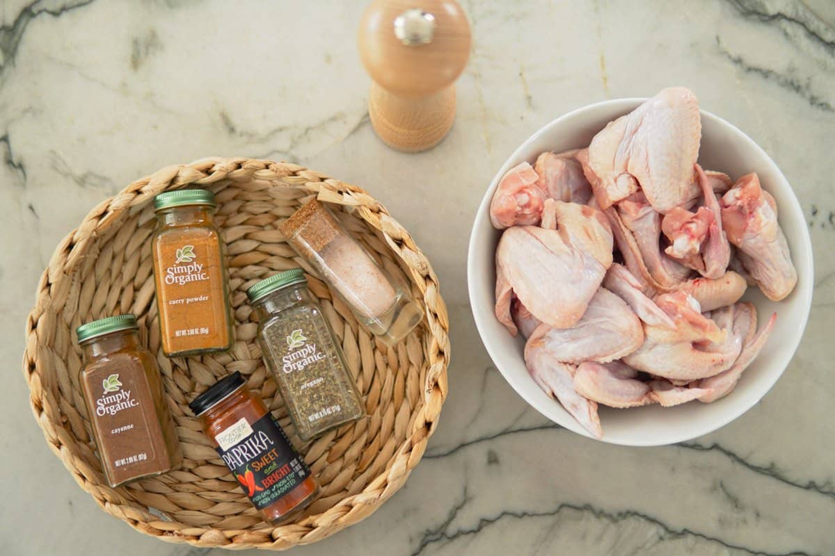 spices in containers and a bowl of raw chicken wings