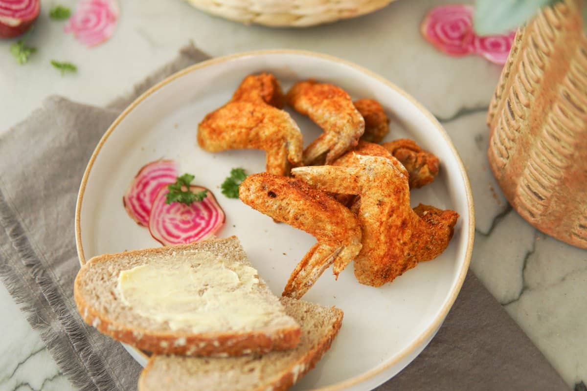 plate of fried chicken wings and a slice of bread