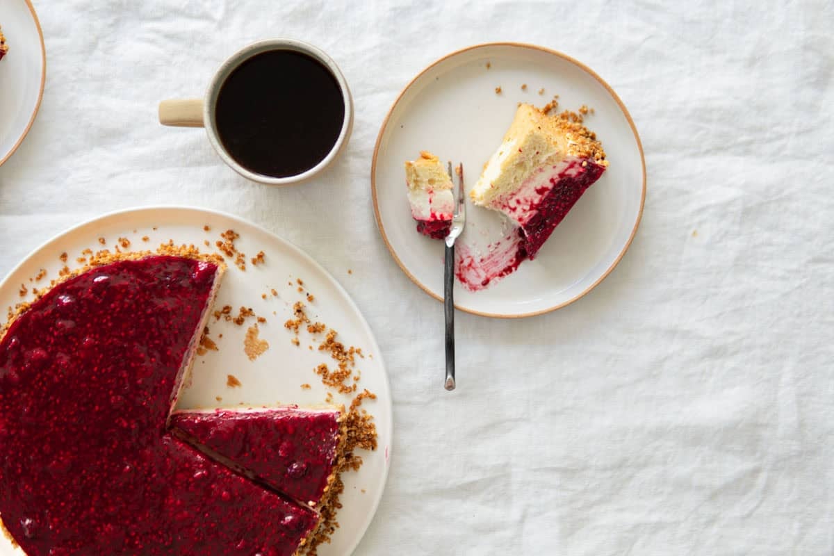 A slice of cake laying sideways on a plate a cup of coffee next to it.