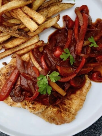 Zigeunerschnitzel on a round plate with potato fries
