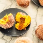 pumpkin donut torn in half sitting on a plate