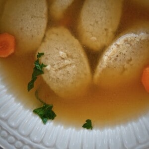 closeup of semolina dumplings in a soup bowl with broth.