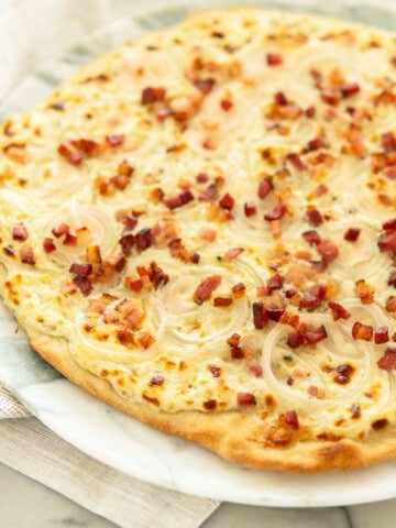 flammkuchen tarte flambee on a white marble plate