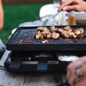sticking a fork into meat on a raclette grill