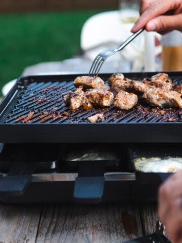 sticking a fork into meat on a raclette grill