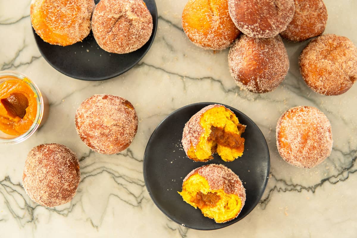 a bunch of sugar-coated pumpkin donuts on the kitchen counter.