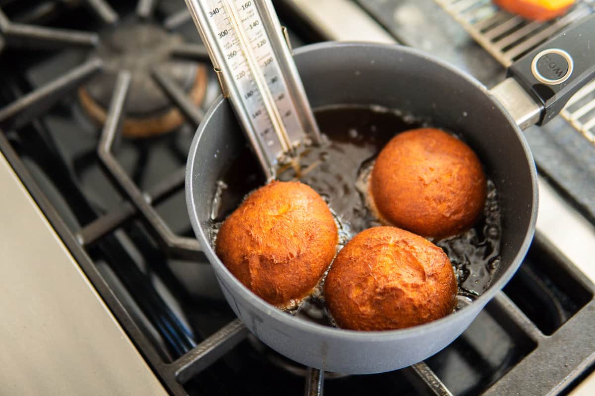 deep frying pumpkin donuts in a pot with a thermometer