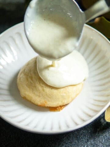 pouring vanilla sauce over German dessert dumplings.