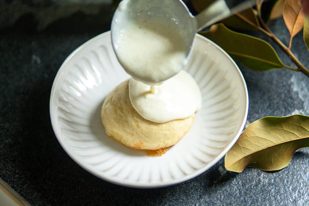 pouring vanilla sauce over German dessert dumplings.