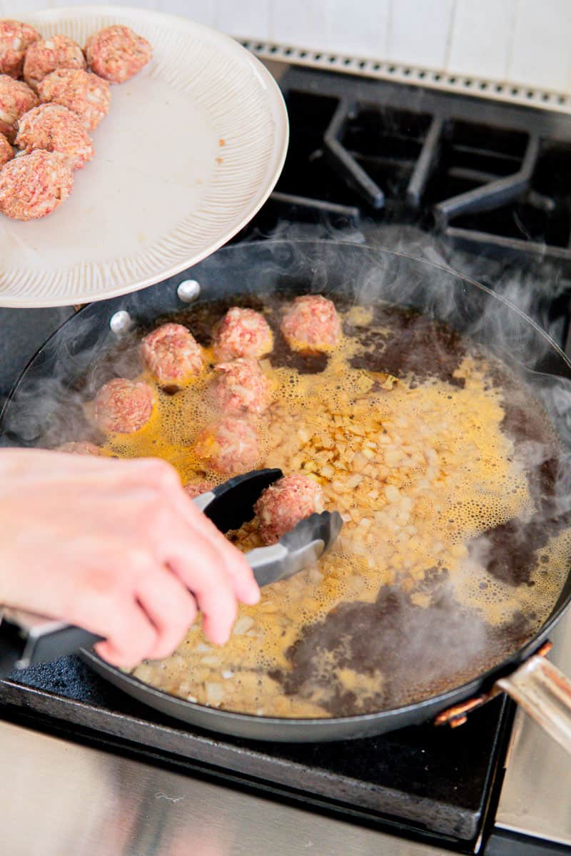 simmering German meatballs in beef broth