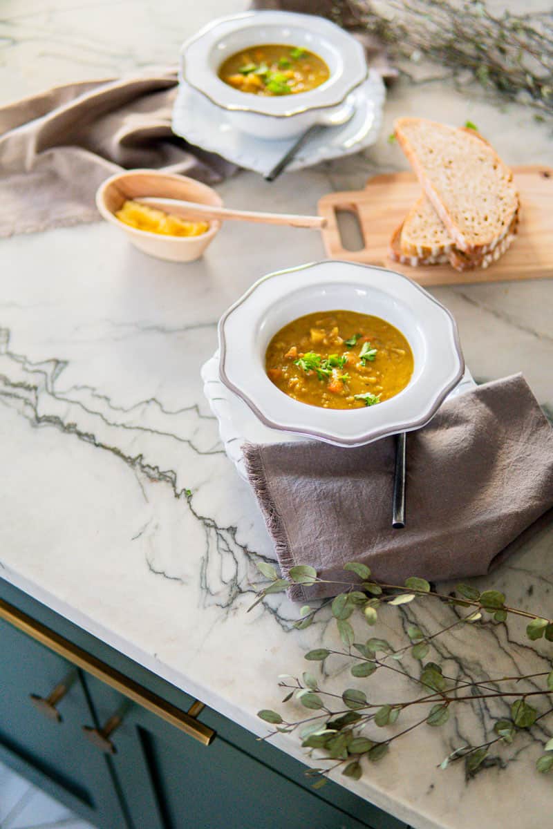 two bowls of split pea soup with bread and butter