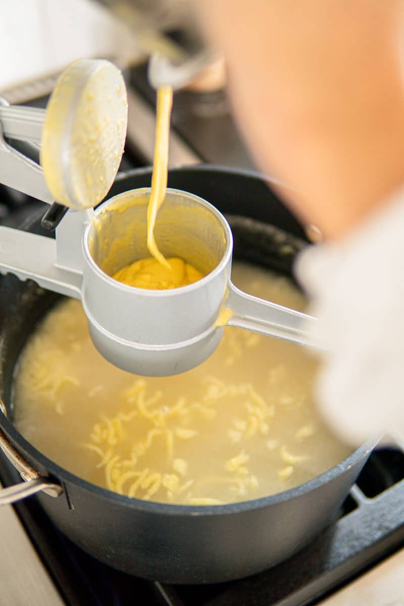 spätzle press in action for making homemade German egg noodles