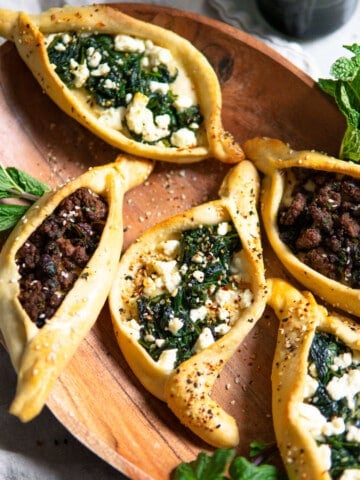 pide flatbread pizzas with different toppings on a wooden serving tray