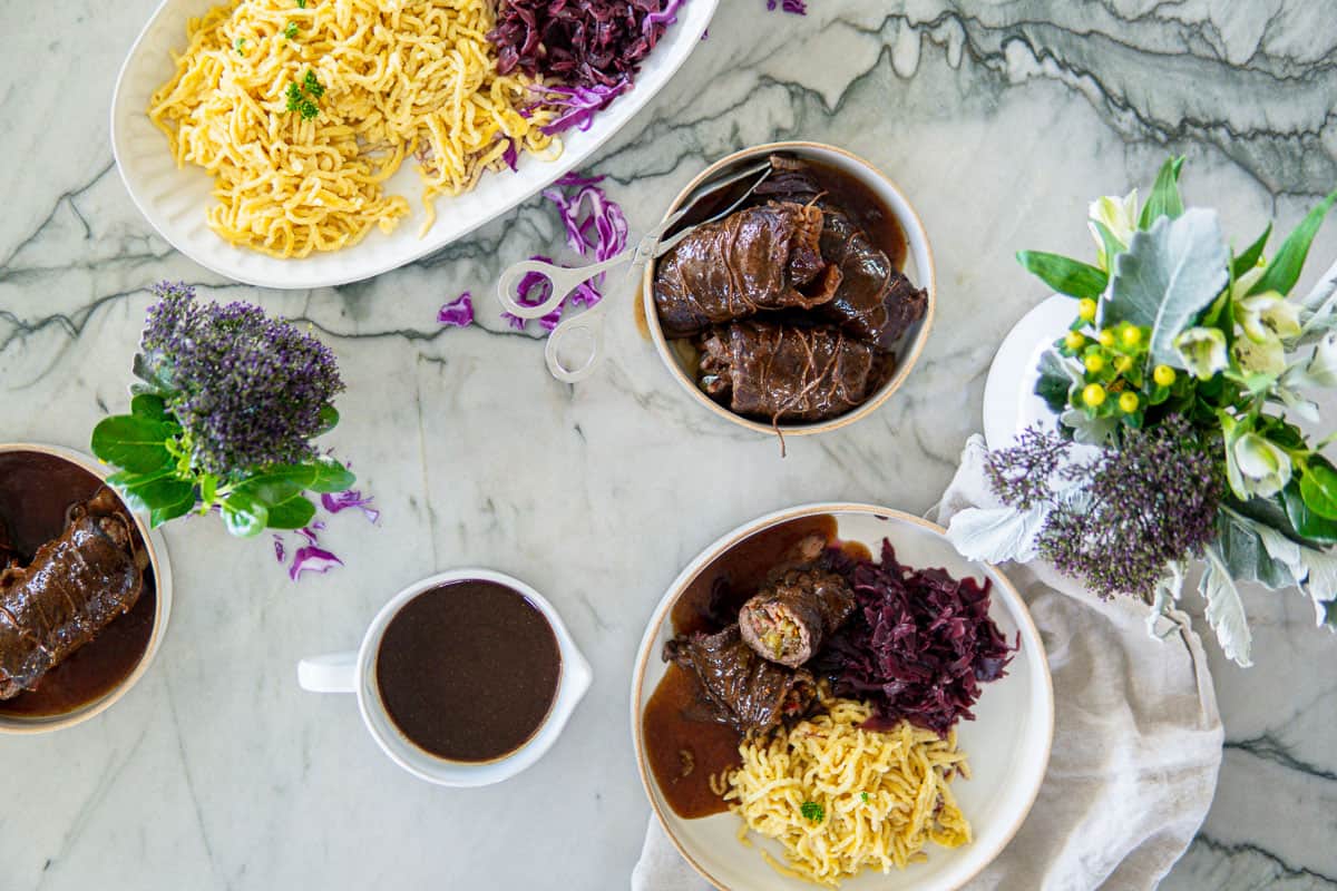 top view of a plate of rouladen and a plate of noodles and cabbage
