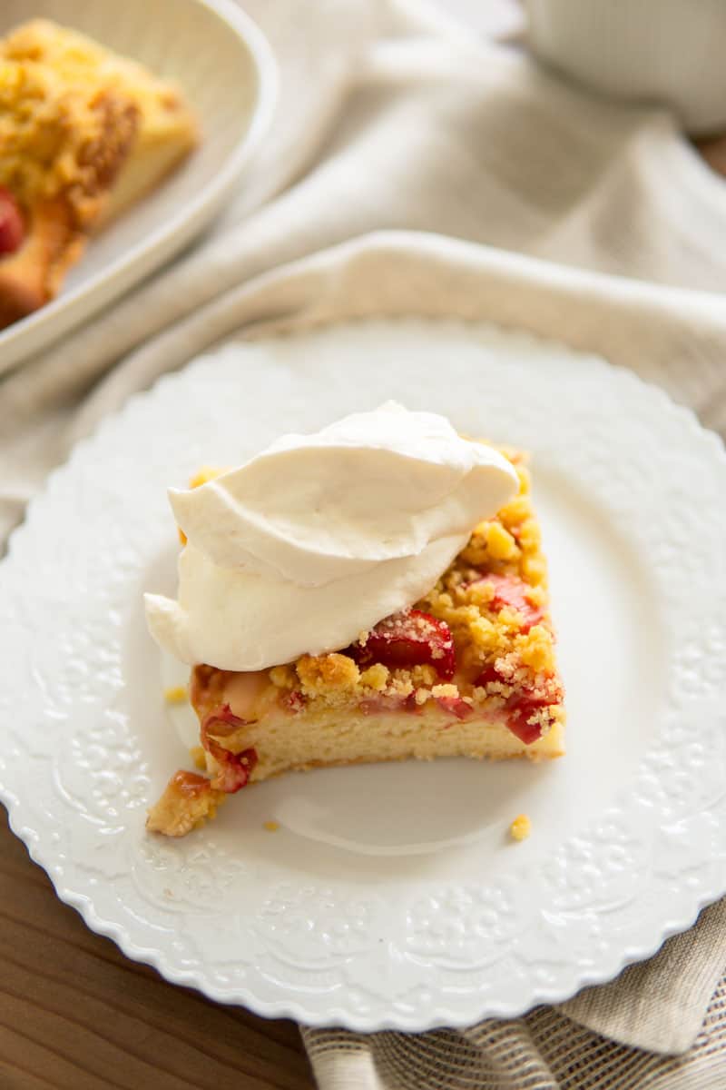 a slice of rhubarb cake topped with whipped cream