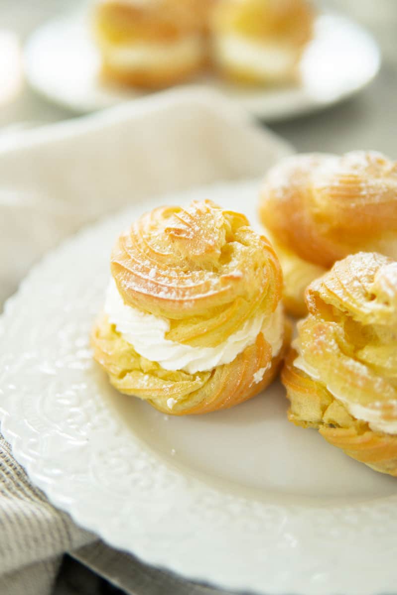 closeup of cream puffs sitting on a white plate