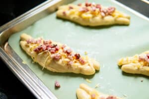 soft pretzels topped with cheese and bacon before baking