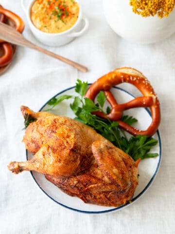 oktoberfest roasted chicken on a plate with a pretzel