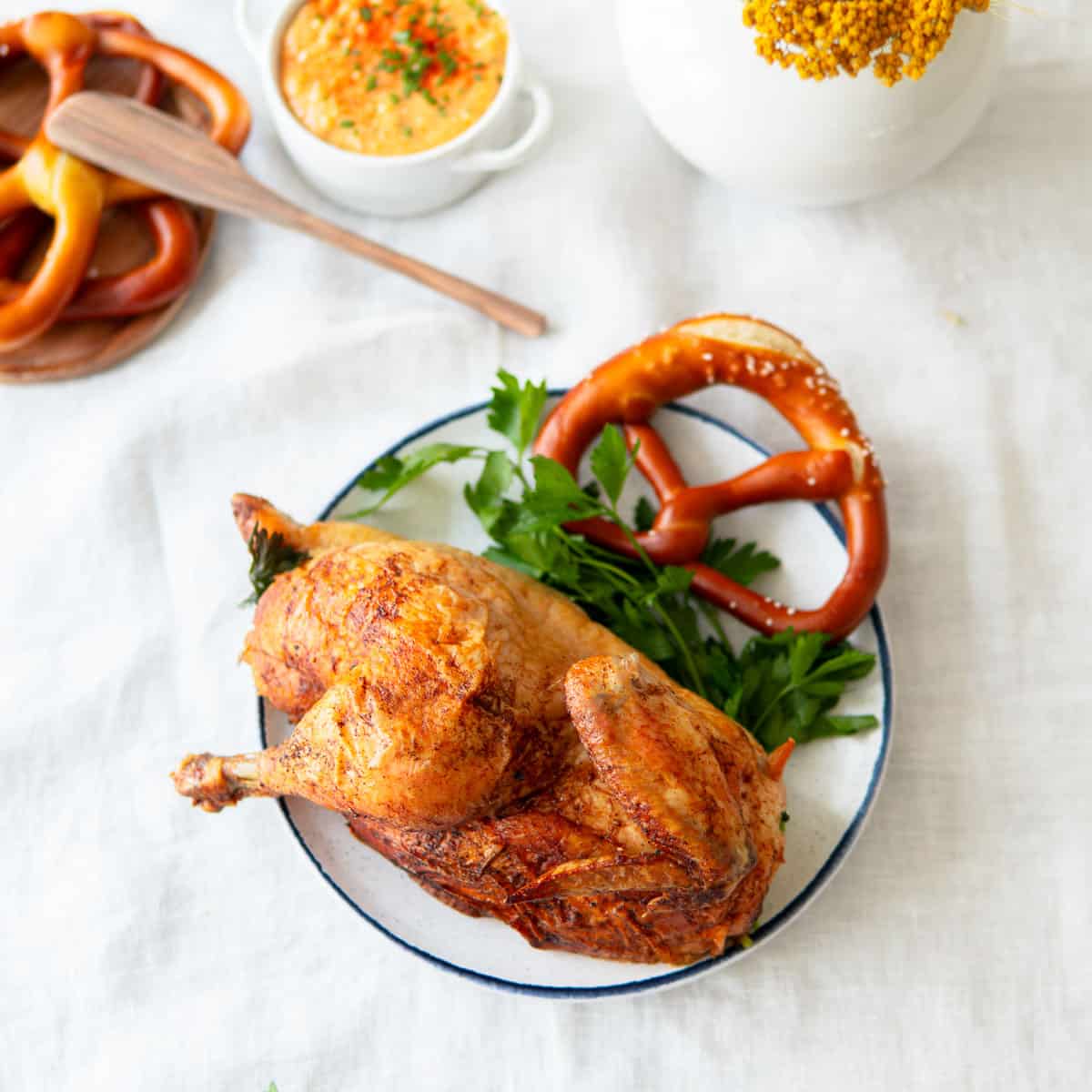oktoberfest roasted chicken on a plate with a pretzel