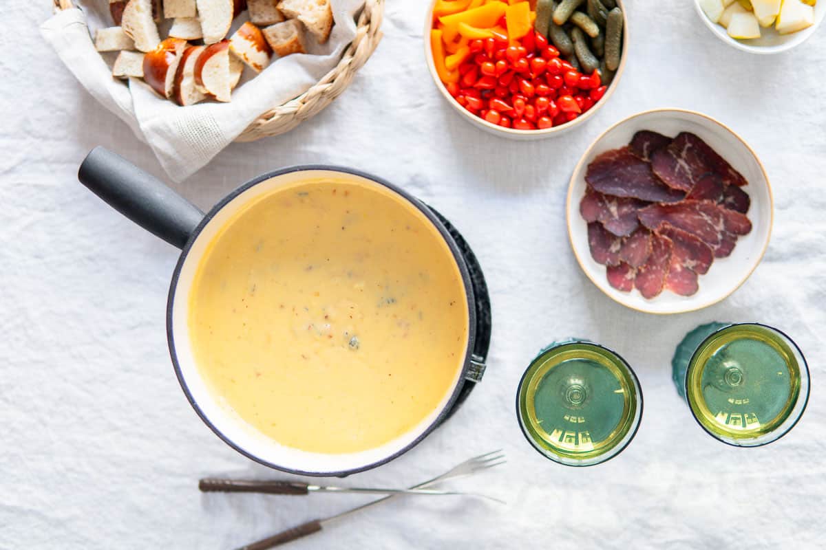Fondue pot with dippers and glasses of wine.