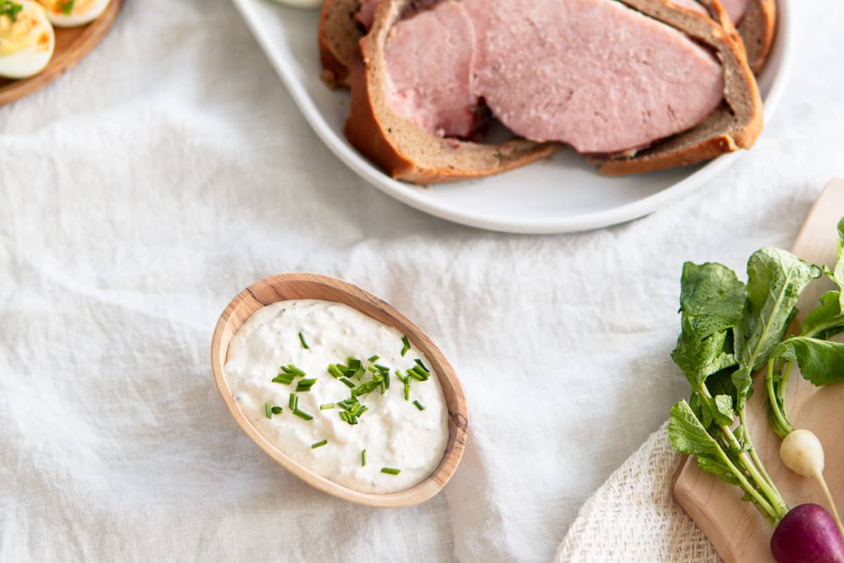 Horseradish cream sauce in a small wooden cup topped with chopped chives.