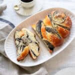 Braided bread with poppy seed filling cut into slices and a cup of coffee.
