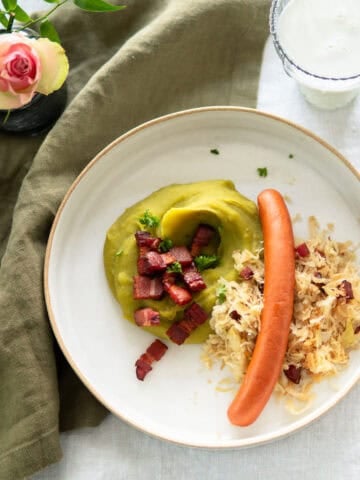 German mashed peas on a plate with sauerkraut, bacon and Wiener sausages.