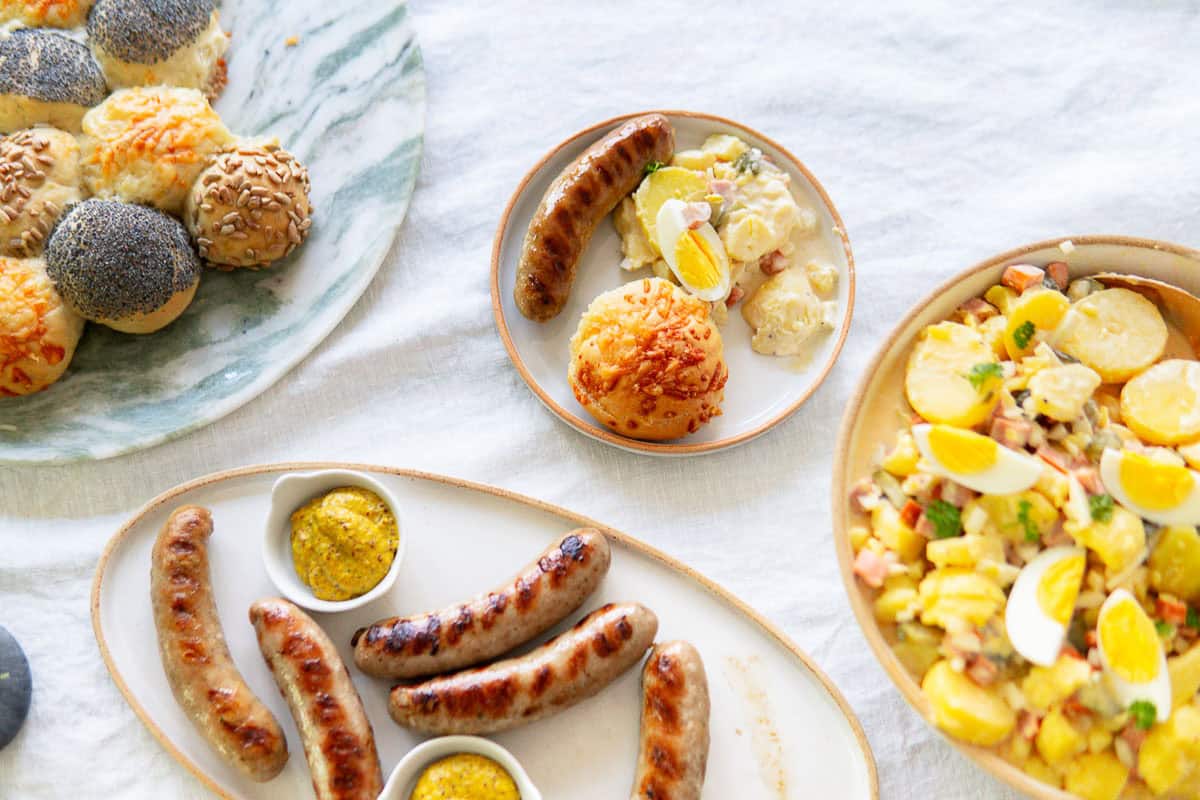 Slider on a plate with a grilled bratwurst and German potato salad.