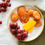 pretzel crackers on a plate with grapes and cheese