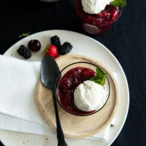 German berry dessert Rote Grütze in a glass topped with vanilla ice cream.