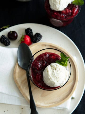 German berry dessert Rote Grütze in a glass topped with vanilla ice cream.