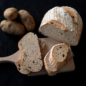 Sliced sourdough potato bread sitting on a wooden board.