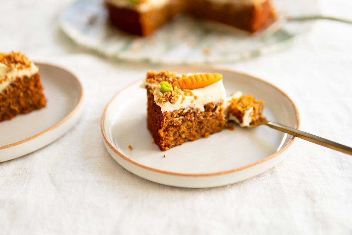 A side closeup view of a slice of carrot cake sitting on a plate.