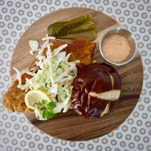A Schnitzel sandwich on a wooden platter.