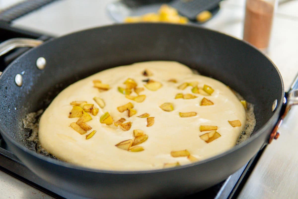 Apple pancake cooking in a skillet.