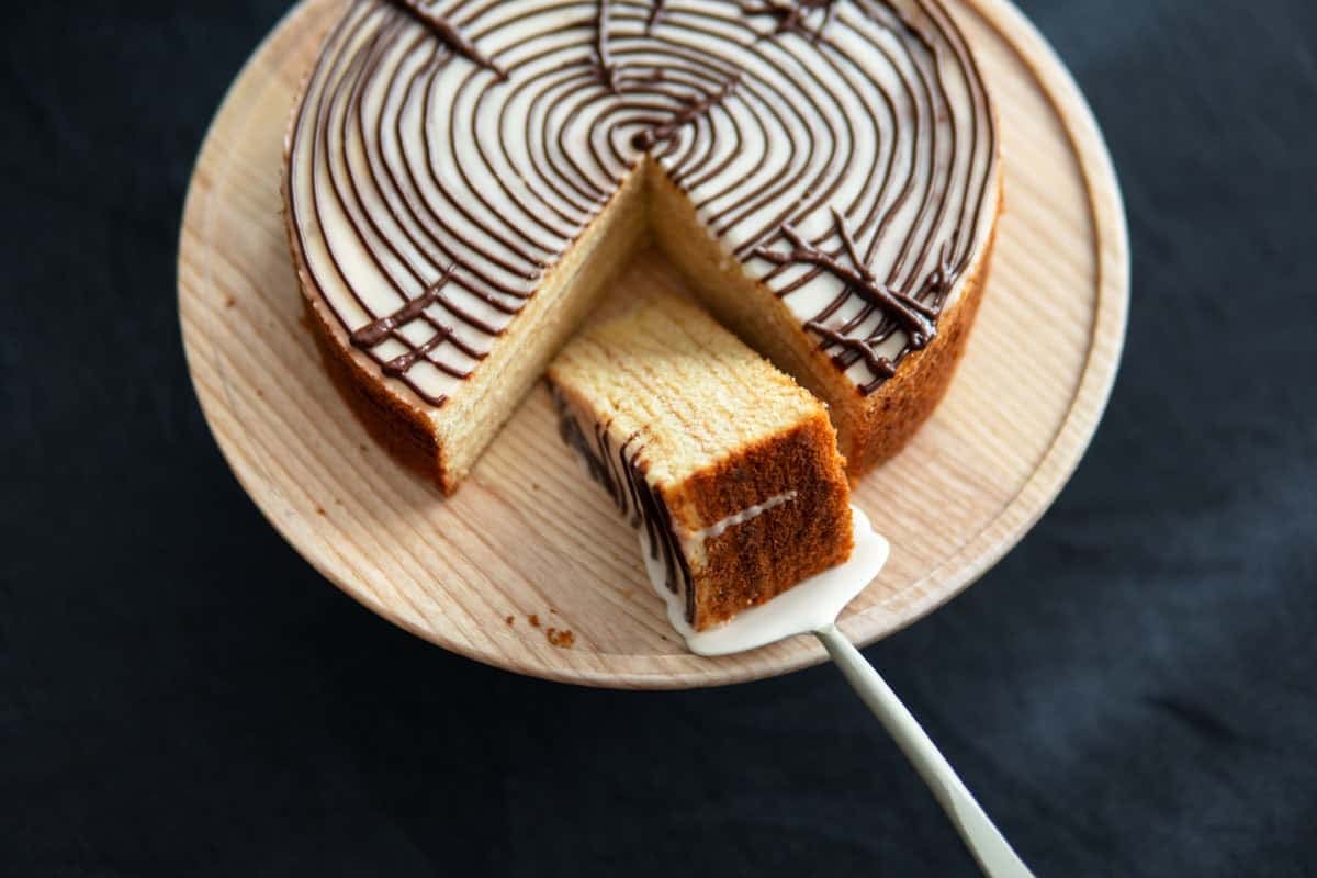 Angled view of a whole tree cake with a slice cut out of it.