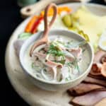 German bologna salad in a bowl next to a charcuterie and cheese plate for a traditional German German bologna salad in a bowl next to a charcuterie and cheese plate for a traditional German breakfast.