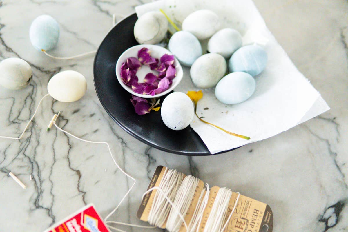 Attaching string to eggs to hang them as decorations.