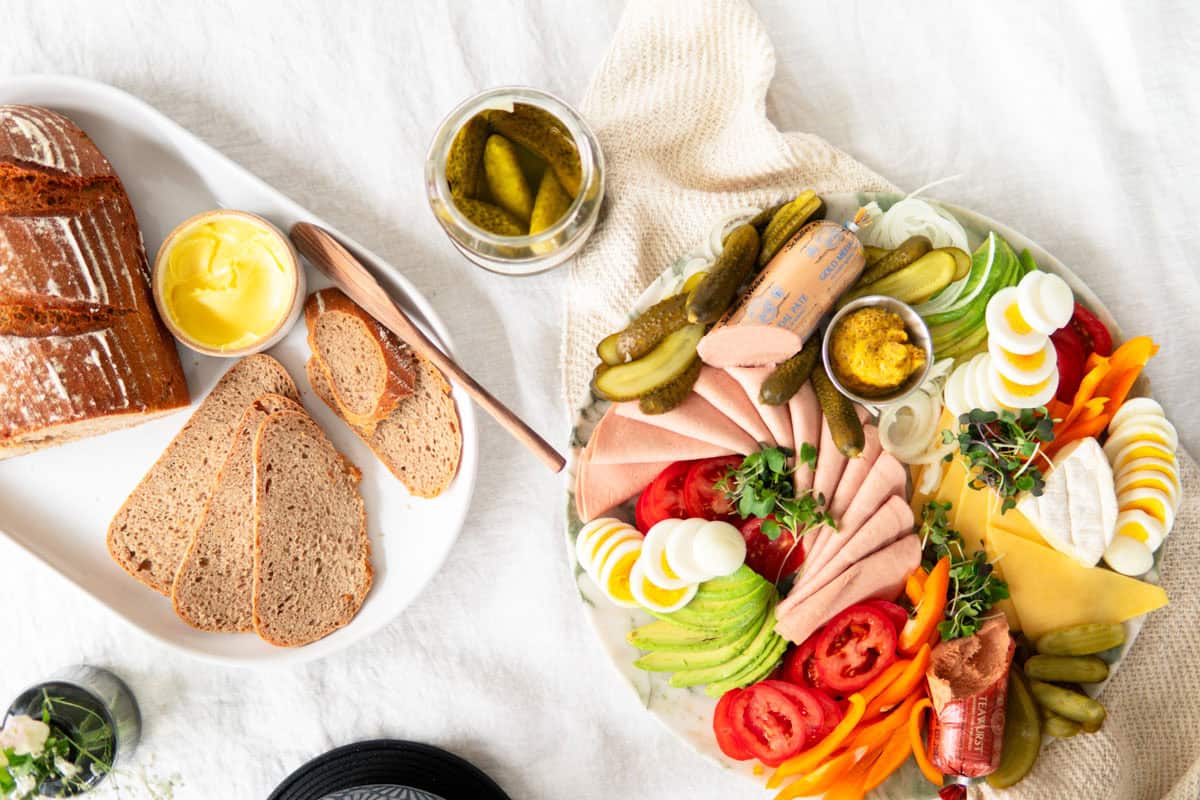 sourdough bread on a platter next to a German breakfast plate with meats and cheeses
