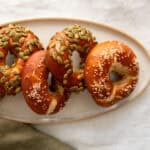 Pretzel bagels sitting on a white stone platter.