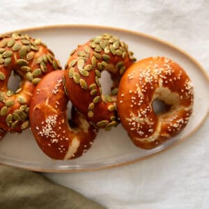 Pretzel bagels sitting on a white stone platter.