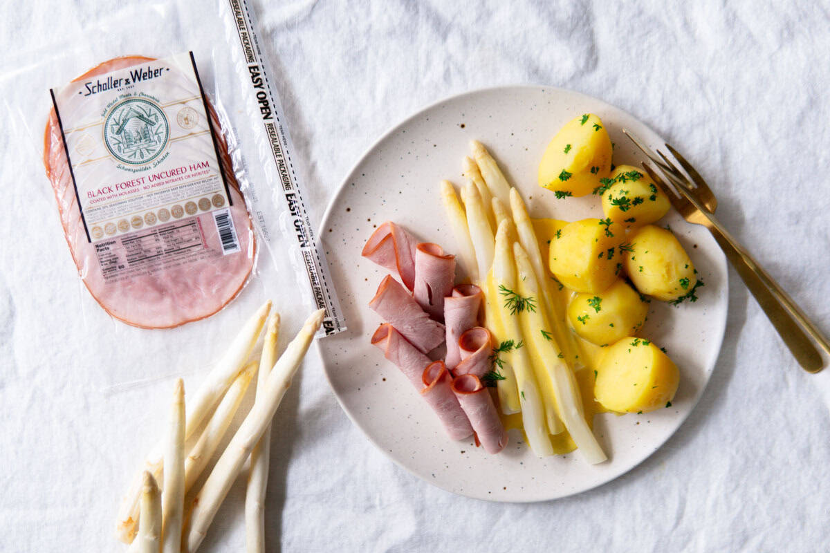 Traditional German white asparagus meal with hollandaise, potatoes and boiled ham.