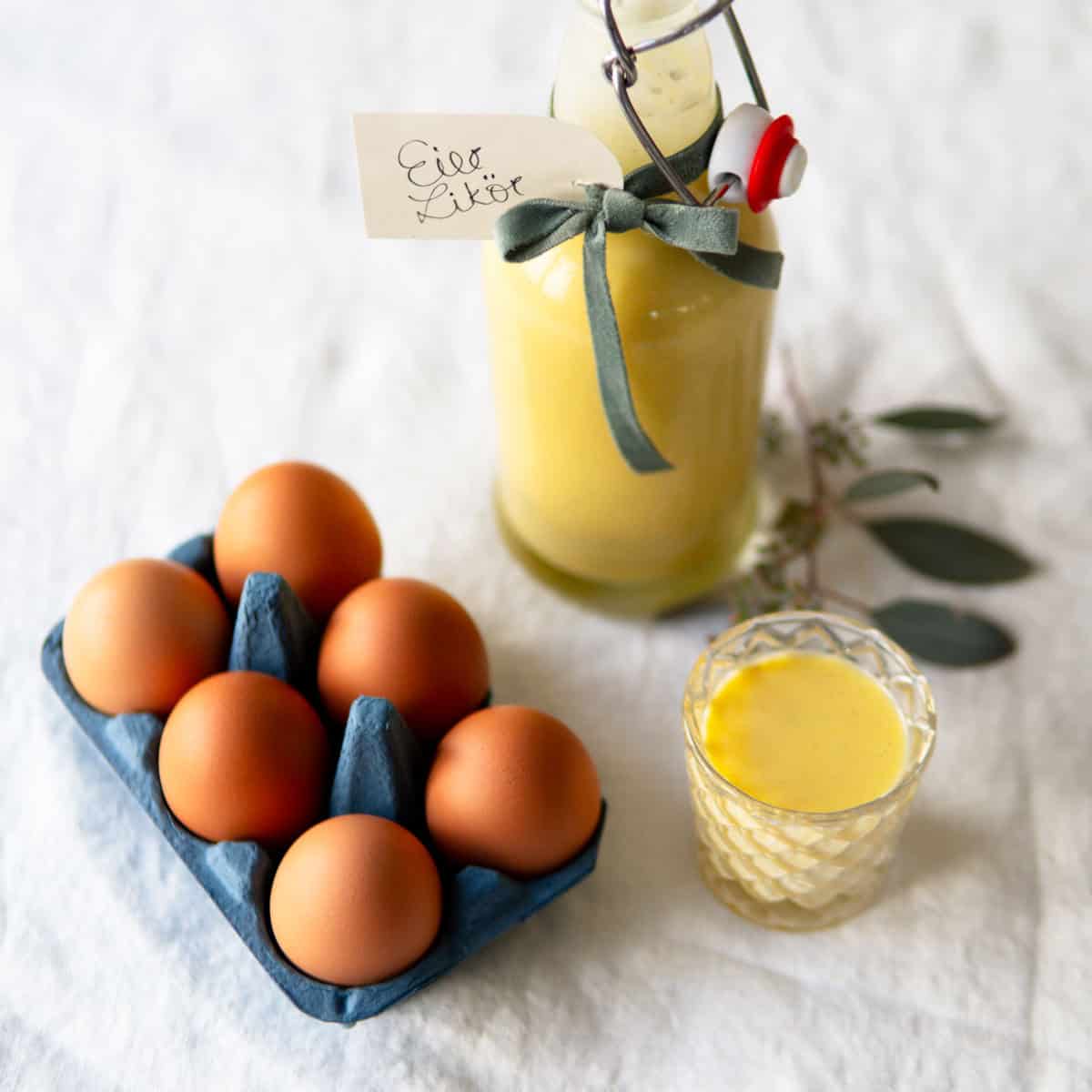 Homemade spiked egg nog in a glass bottle with some eggs on the side.