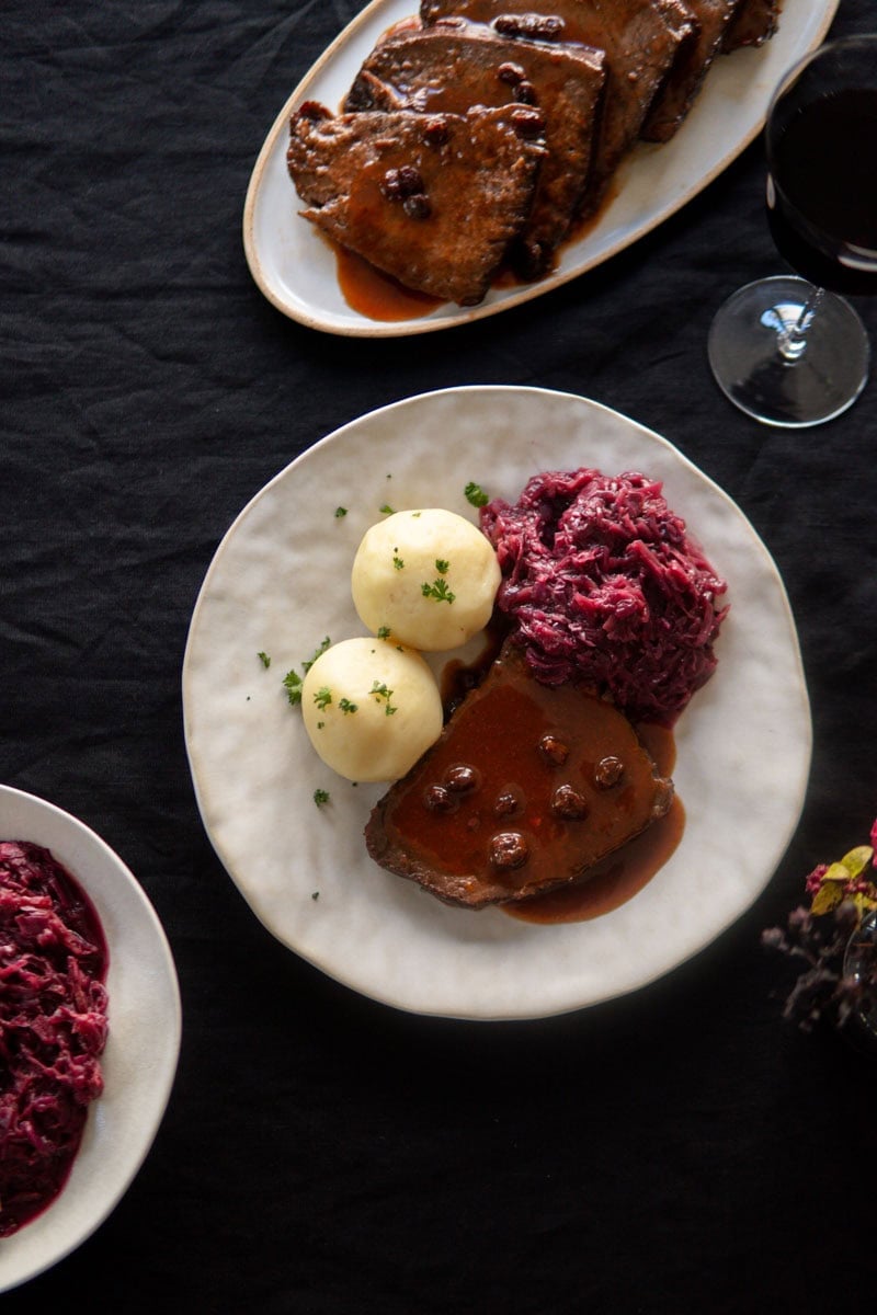 Sauerbraten on a plate with German potato dumplings and braised red cabbage.