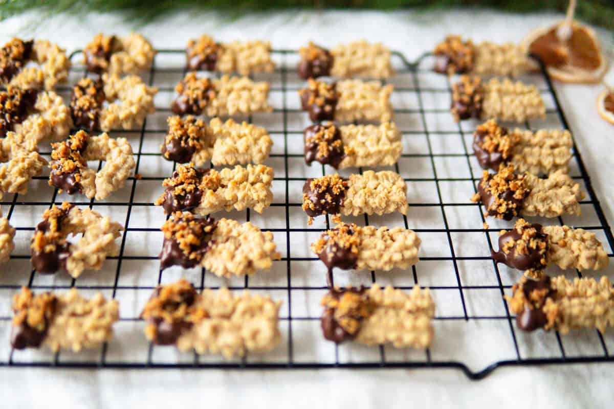 German spritz cookies partially dipped in chocolate and sprinkled with caramelized nuts.