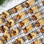 German spritz cookies partially dipped in chocolate and sprinkled with caramelized nuts.