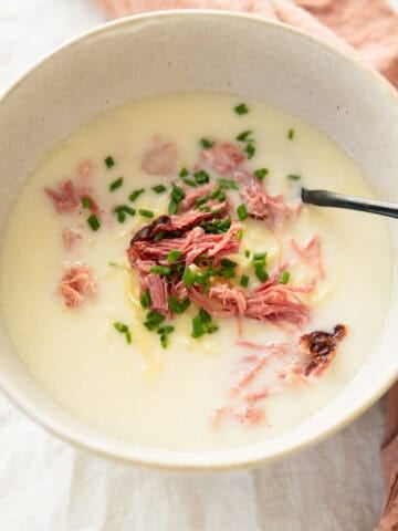 bowl of smoked pork soup with noodles and topped with chives.